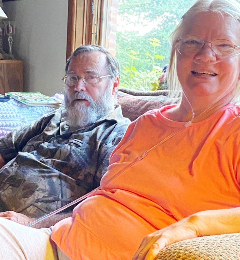Anxiously waiting for a call — Ed and Chris Bacon relax on the couch in their rural Cass County home as they talk to the Star-Gazette’s Jan McGovern about Chris’ need for a double lung transplant. (Photo by Jan McGovern.)