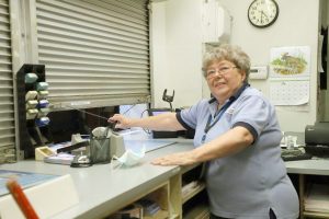 It’s Quittin’ Time! — With the clock on the wall reading 4:31 p.m, Rose Black closes the service window at the Beardstown Post Office for the last time on Friday, July 3, ending her remarkable 47-year career with the U.S. Postal Service.  (Photo by Brian DeLoche)
