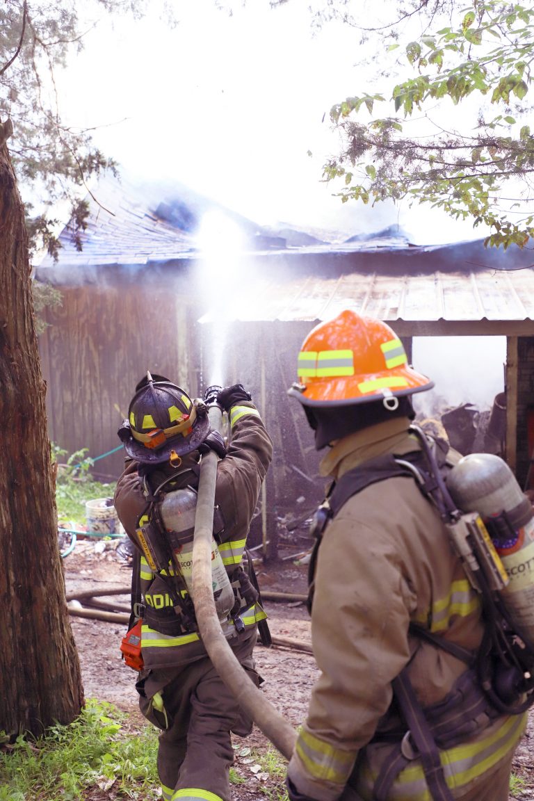 Hitting the Roof — Firefighters pour water into the collapsing roof line of Earl Richardson Jr.’s rural Chandlerville home July 29.  Fire believed to have begun in Richardson’s car spread to the garage and then to the home. (Photo by Brian DeLoche.)