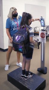 The new normal — Beardstown students returning to school Monday stood in line for temperature checks before being admitted to the building.  Temperature scanning kiosks scan each student and record their temperature along with a photograph.  All persons entering the district’s buildings must have a temperature scan before being admitted. (Photo by Brian DeLoche.)