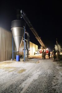 Hot Air — Beardstown firefighters were called to the Falcon Protein processing plant on Kent Feed Road south of Beardstown Monday night where a fire had broken out in the facility’s air handling units. Above, the department’s ladder truck was needed to reach the top of an exterior collection unit and douse the fire inside. (Photo by Brian DeLoche.)