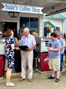 Arenzville Mayor Ron Kershaw reads a proclamation declaring May 22, 2022, “Cheryl Lemke Day” as Lemke and Isaac French, of Isaac’s Coffee Shop listens. Lemke is the WICS News Channel 20 meterologist. Isaac has watched her deliver the weather news for several years and enjoys watching the forecast with enthusiasm.   Photo submitted
