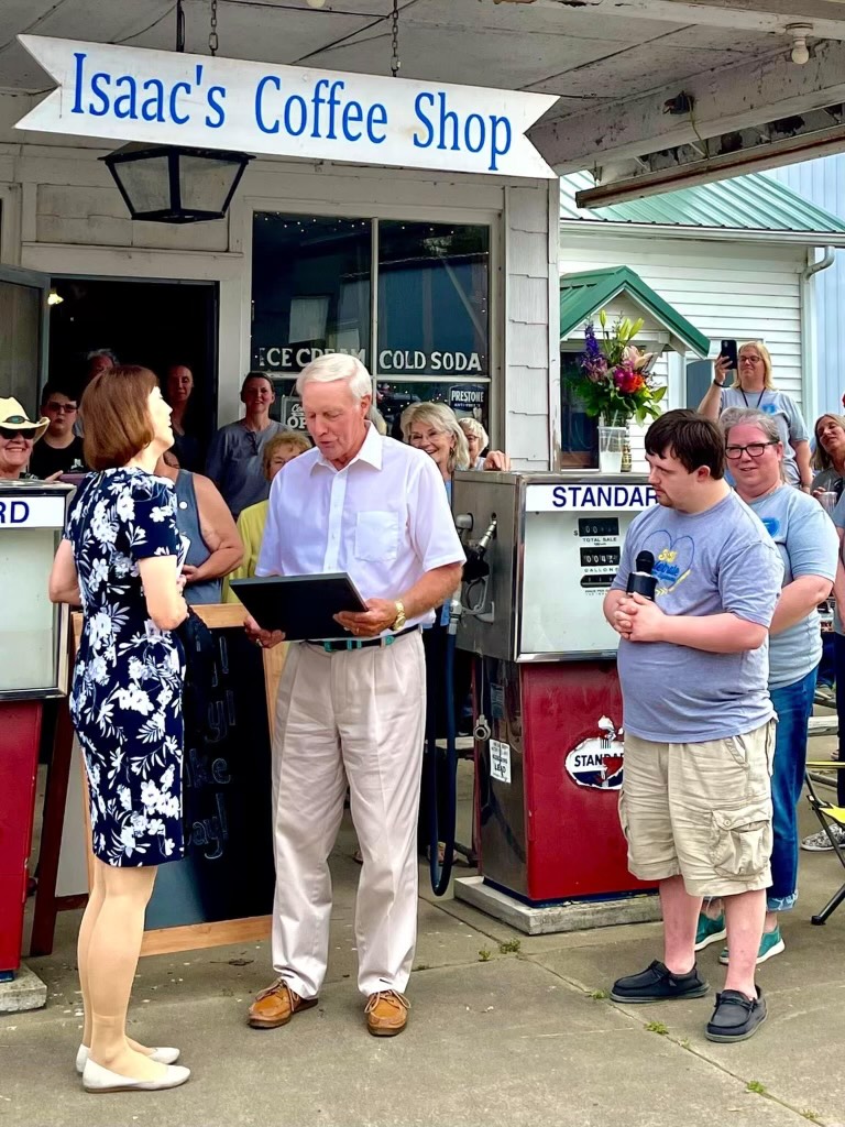 Arenzville Mayor Ron Kershaw reads a proclamation declaring May 22, 2022, “Cheryl Lemke Day” as Lemke and Isaac French, of Isaac’s Coffee Shop listens. Lemke is the WICS News Channel 20 meterologist. Isaac has watched her deliver the weather news for several years and enjoys watching the forecast with enthusiasm.   Photo submitted