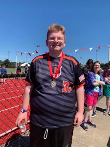 C.J. Evans is all smiles with a Gold Medal around his neck for taking 1st Place in the softball throw at the Special Olympics of Illinois Summer Game.