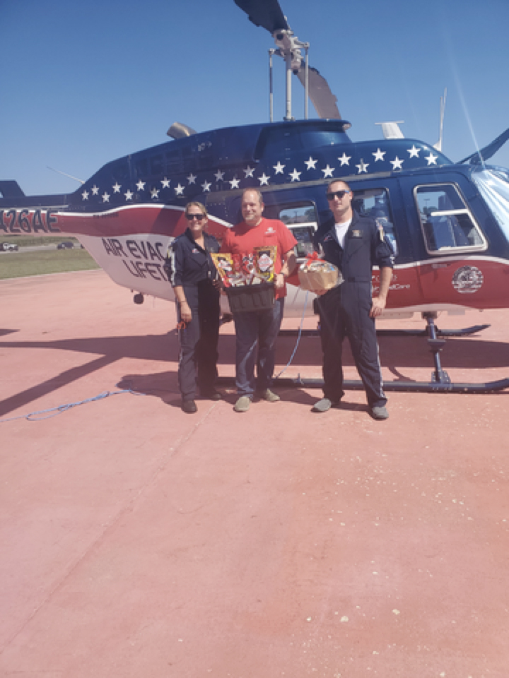 Air Evac representatives, Morgan Vetter, left, and Adam Crum, right, accept a gift basket presented by Buchheit of Jacksonville Manager Kurt Beckmann, center.