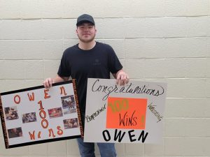 Beardstown senior Owen O'Hara is shown with a poster and a picture collage celebrating the 100th win of his wrestling career.