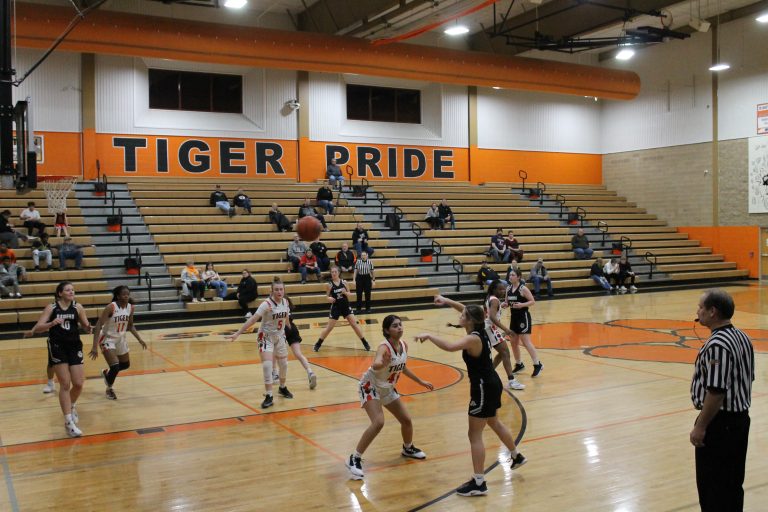 Ari Garcia guards the ball while Bertille Kayembe (#11) and Kylynn Maltby (#5) protect the lane in girls basketball action against Midwest Central.
