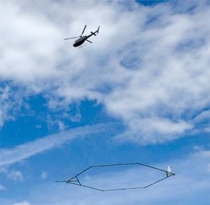 A low-flying helicopter towing a geophysical device collects scientific data for salinity and aquifer mapping.