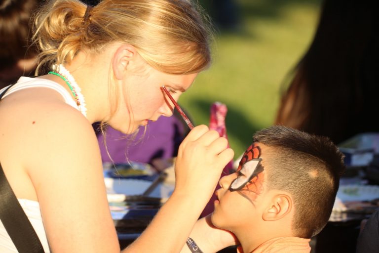 Emma Davis paints a Spiderman mask on a young man during last week’s Family Friday Carnival in the city square. The event featured bounce houses, sack races, hula hoops and sidewalk chalk art. Photo by Brian Deloche