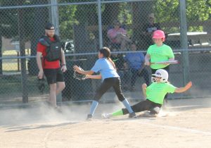 Safe!  The runner beats the throw and scores on a passed ball in Little League girls softball action.