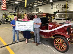MEC Director Gary Martin and General Manager Alisha Anker presented the donation to Ashland Fire Protection District Chief Tyler Lathom in front of the original fire engine, which is 100 years old next month.