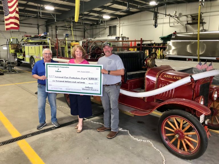 MEC Director Gary Martin and General Manager Alisha Anker presented the donation to Ashland Fire Protection District Chief Tyler Lathom in front of the original fire engine, which is 100 years old next month.