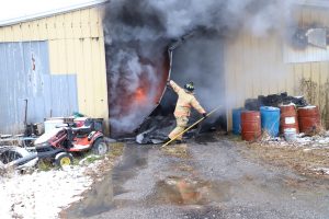 A firefighter battles the blaze at a structure fire on Kent Feed Road.