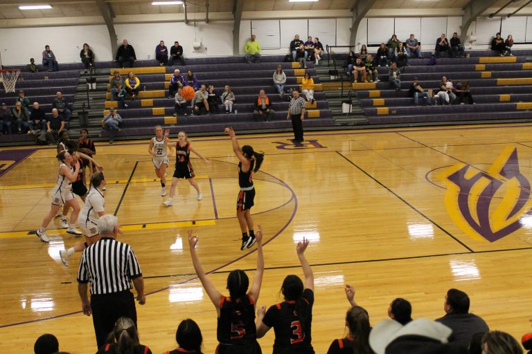 Ashley Gil launches a three-pointer in front of an excited Tiger bench.