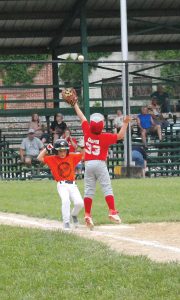 The first baseman leaps high for the throw as the runner bares down on him in minor league action.