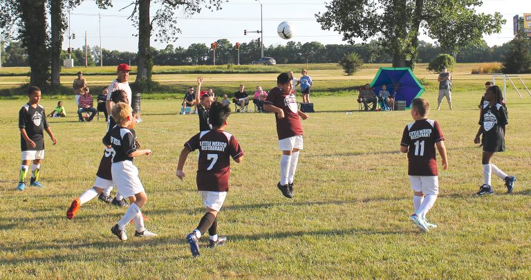 A young player for the Little Mexico team sends the ball skyward with a header.