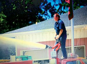Pictured above, Lee Burrus stands atop a firetruck, spraying water. Photo from Arenzville Fire Department Facebook.