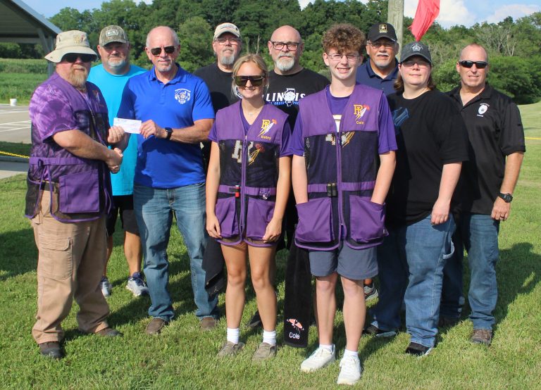 The Spoon River Valley Fraternal Order of Police Lodge 427 presented Rushville-Industry trap coach Calvin Phillips (left) a $500 check as a donation to the program on Saturday, July 13. Presenting the check was Lodge 427 President Donald “Ike” Hackett. Also pictured in the front row are trap team members Kinley Price and Cole Worley, along with FOP Lodge 427 Secretary Amanda Onken. In the back row are assistant trap coach Kevin Price, Lodge Treasurer Randy Zimmerman, First Vice President Andy Steck, McDonough County FOP trustee Jim Percy, and Rushville Police Chief Rick Wright. Trap shooting is an emerging sport with the IHSA so all the trap teams are on their own to raise money.