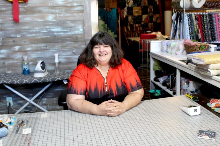 Carrie Whitford sits at a cutting table at Prairie Rows Quilting and Crafting in Virginia. Photo by Carty