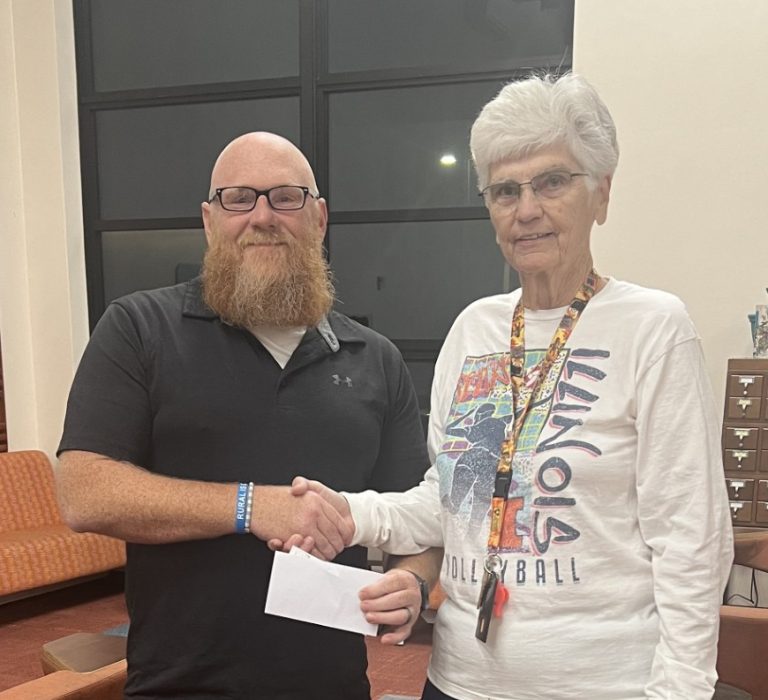 Casey French,Virginia CUSD 64 Board of Education,l is pictured left, receiving a donation from long time Virginia educator, coach and community member, Karen McClure, right.