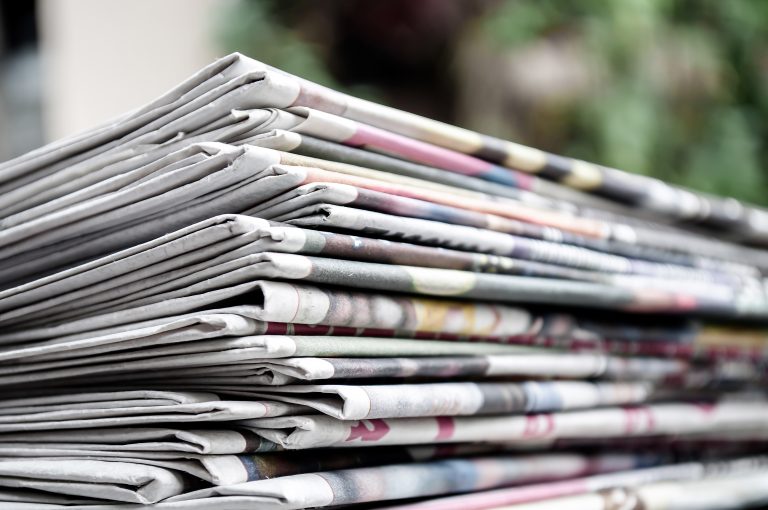 Newspapers folded and stacked on the table with gardenor green